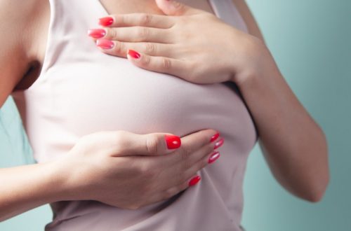 a woman with red nail polish holding her stomach