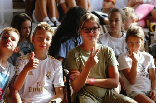 Cheerful group of children sitting together at an indoor event, showcasing friendships and diversity.